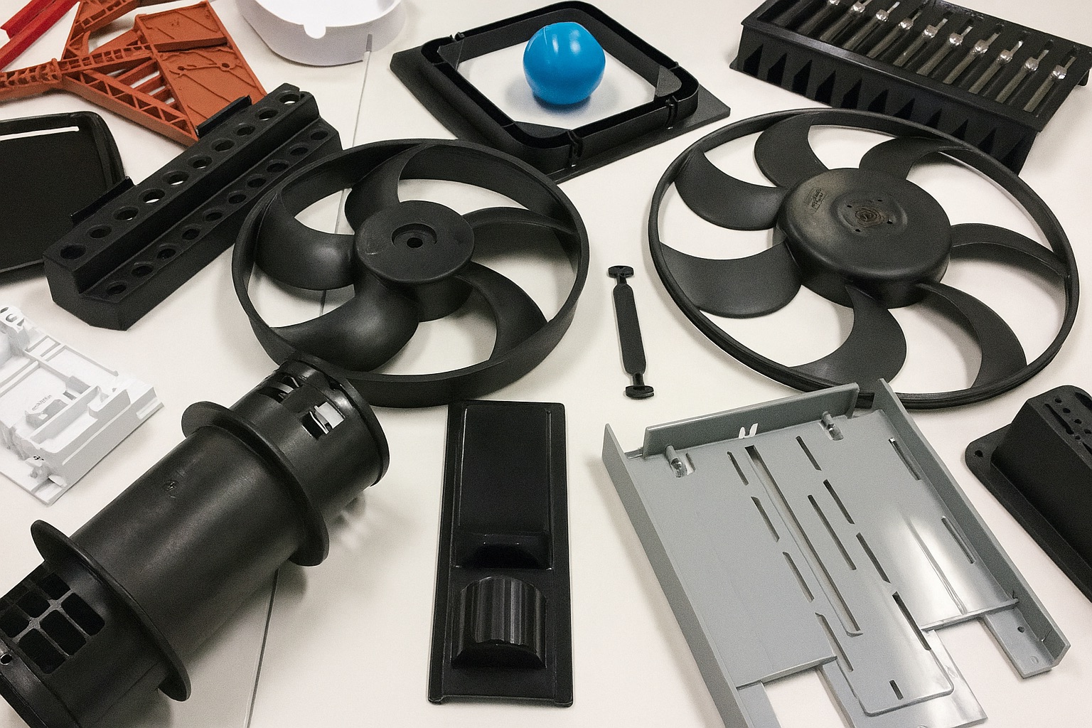 Assorted injection-molded parts—fan blades, housings, brackets, trays
