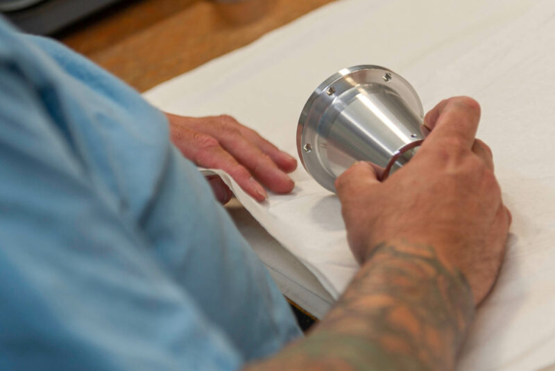 Operator performing quality inspection on a CNC-turned aerospace-grade metal component.